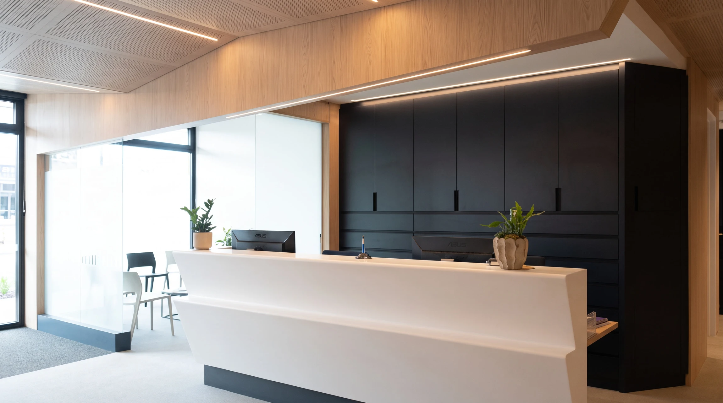 Espace d'accueil professionnel moderne avec banque d'accueil courbe en bois foncé et structure noire