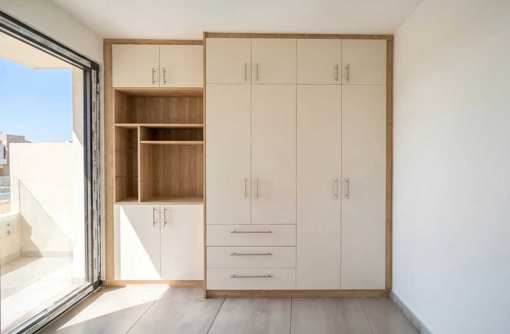 Salon minimaliste vide, mur gris clair, parquet chêne clair