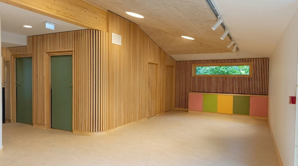 Salon minimaliste vide, mur gris clair, parquet chêne clair