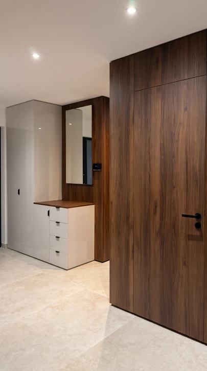 Photographie en haute résolution d'une porte intérieure en bois sur mesure, présentant plusieurs finitions de bois visibles (bois brut naturel, bois vernis brillant, bois menuisé). La porte doit être ouverte ou semi-ouverte, installée dans un cadre d'intérieur épuré et moderne, montrant son intégration harmonieuse dans un décor résidentiel. L'éclairage doit mettre en valeur les textures et veinage du bois, ainsi que la qualité artisanale de la menuiserie. Pas de texte, logo ou signature visible.