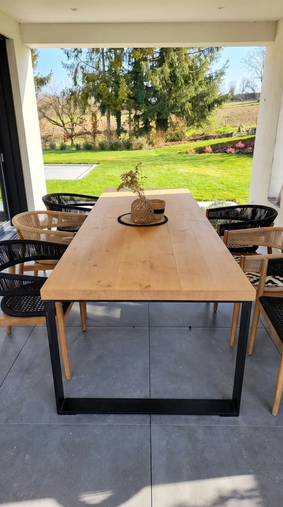 Intérieur moderne avec console en bois massif, fauteuil mid-century en tissu beige et structure noyer, plante verte en pot céramique noir, parquet chêne point de Hongrie, murs blancs avec cadre artistique encadré noir