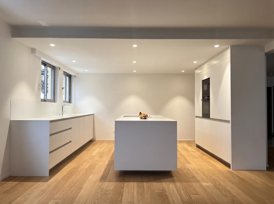 Cuisine aménagée en combles avec plan de travail vert olive en L, façades de meubles bas en stratifié imitation noyer, poignées noires