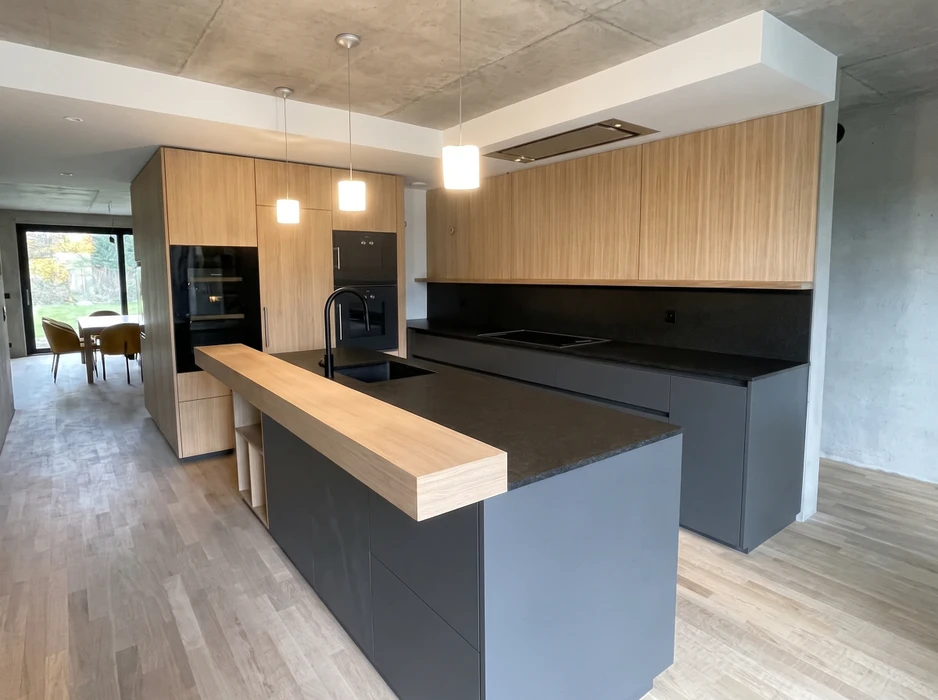 Cuisine aménagée en combles avec plan de travail vert olive en L, façades de meubles bas en stratifié imitation noyer, poignées noires