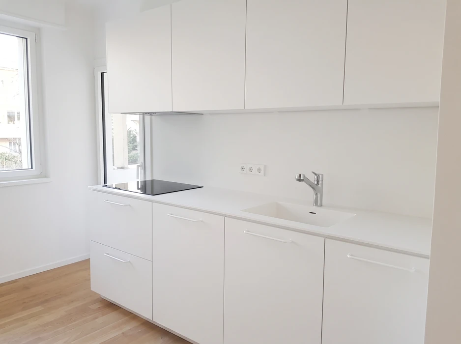 Cuisine aménagée en combles avec plan de travail vert olive en L, façades de meubles bas en stratifié imitation noyer, poignées noires