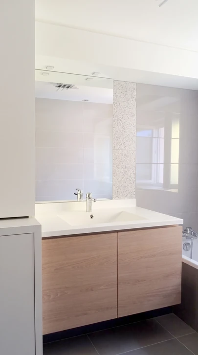 Salle de bain moderne avec vasque blanche ovale posée sur meuble-vasque en bois à lamelles verticales